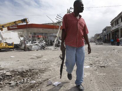 Un hombre armado camina por una calle del centro de Puerto Príncipe vigilando para evitar el saqueo de los comercios destruidos por el terremoto.