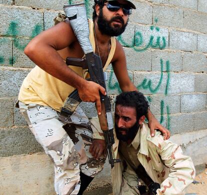 Un combatiente anti-Gadafi consuela a su camarada después de que su posición fuera atacada a seis kilómetros de Sirte.
