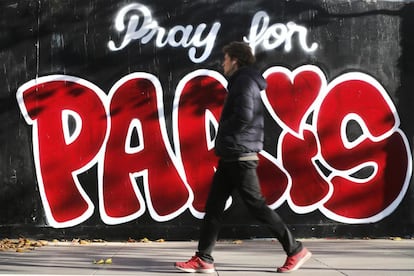 Un hombre pasa ante un grafiti en el que se lee "Reza por París" en una pared de la capital francesa.