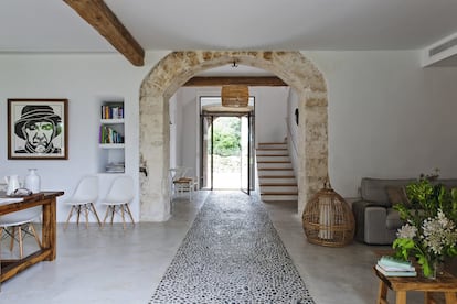 En el hall, un arco de piedra crea un doble espacio, con una puerta de cristal que da luz a la estancia. La escalera realizada con baldosas típicas mallorquinas es de nueva construcción.