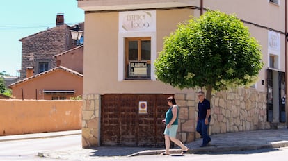 Dos personas pasean por Sigüenza (Guadalajara) el pasado 22 de julio delante de una casa con el cartel de 'Se alquila', apenas visible debido al paso de los años.