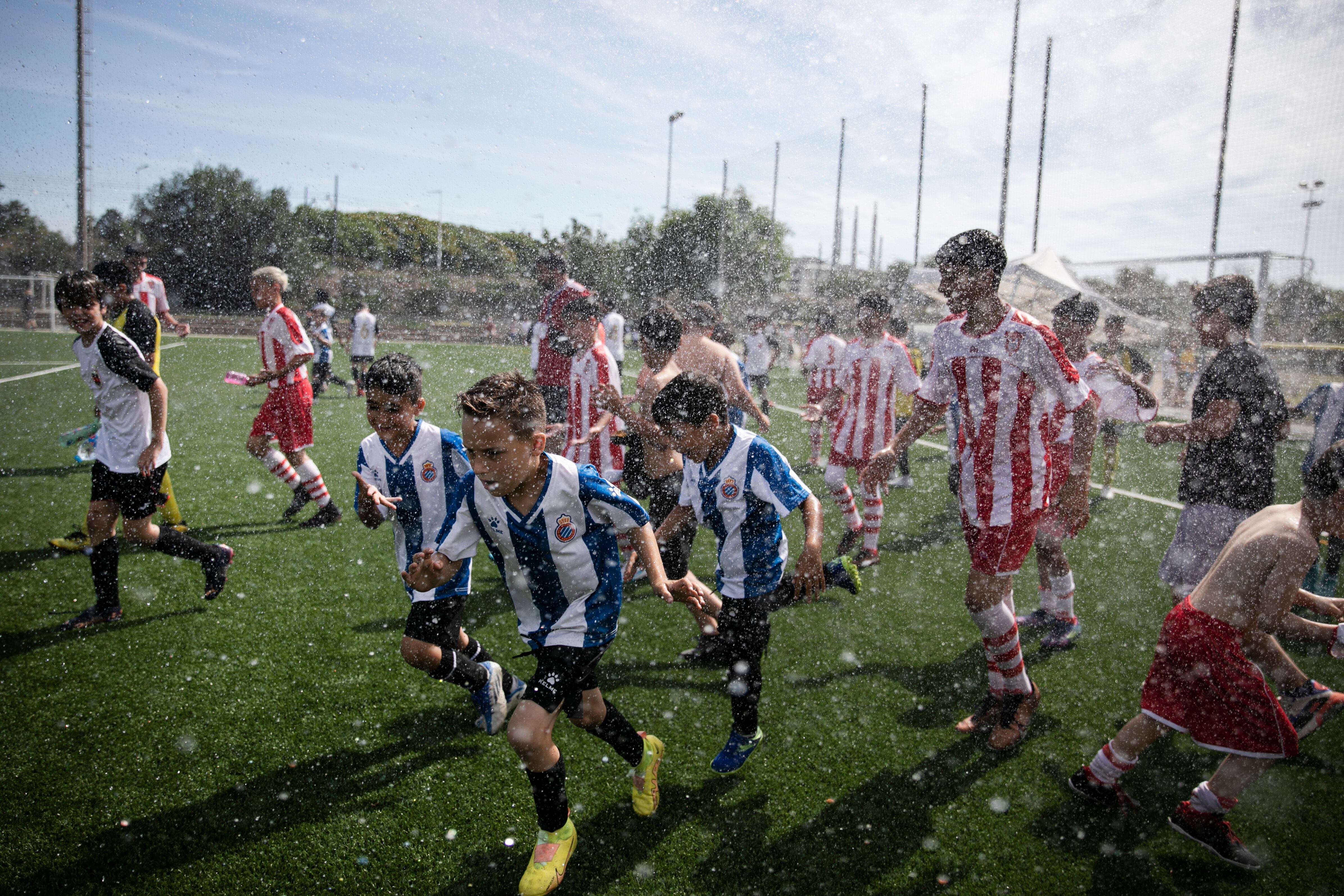 En la imagen los niños participantes del torneo juegan con agua durante una pausa. 