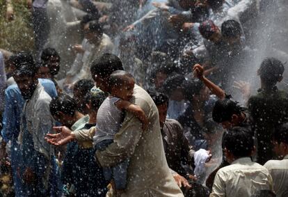 Hombres y niños se refrescan de la ola de calor rociados con agua de una tubería que gotea en Karachi, Pakistán.