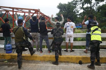 Soldados de la policía de Mawari, en la isla sureña de Mindanao en Filipinas, cachean a un grupo de civiles.