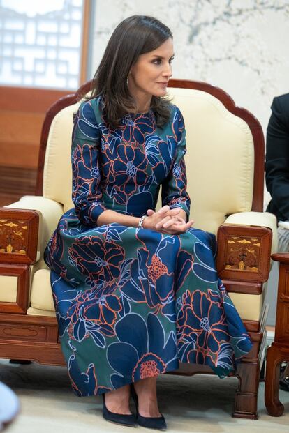 Doña Letizia es muy dada a repetir prendas y sorprendió una vez más con este vestido 'midi' de Carolina Herrera. Un diseño de manga francesa y estampado floral en azul, verde y naranja, que durante su viaje a Corea del Sur combinó con accesorios en azul marino y un conjunto de pendientes y pulsera de diamantes y zafiros.