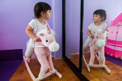 Sira se mira al espejo con curiosidad mientras monta sobre su caballo balancín.