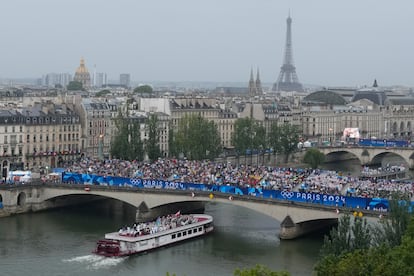 Centenares de personas aplauden desde uno de los puentes la llegada de un barco, durante la ceremonia inaugural de los Juegos Olímpicos de París 2024 en el Sena, París (Francia), el pasado viernes.