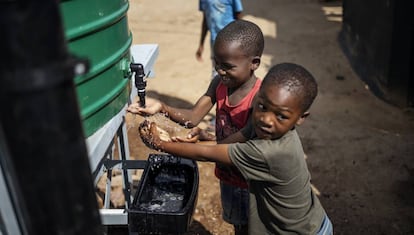 Unos niños se lavan las manos en un asentamiento informal de Sudáfrica.