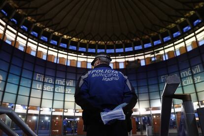 A municipal police office waits to hand out masks at Atocha station.