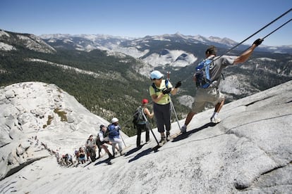 Para contemplar el valle de Yosemite, en California, desde la cima del Half Dome hay que subir primero por su empinado lomo de granito. El tramo final de la ascensión, vertical y aéreo, está equipado con un sistema de cables que facilitan el aseguramiento de montañeros y turistas.