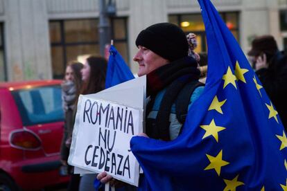 Un manifestante porta una bandera europea y un cartel que reza 'Rumania no se rinde', en febrero en Bucarest.