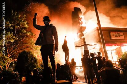 Los manifestantes levantan los puños desafíantes frente a un restaurante de comida rápida en llamas cerca de la comisaría de policía de los oficiales que arrestaron a George Floyd, en Minneapolis, Minnesota, el 29 de mayo de 2020.