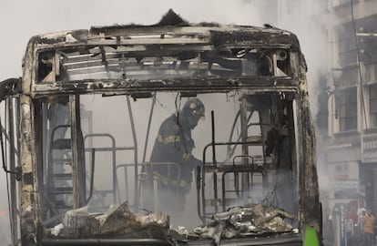 Bombeiro trabalha em ônibus que foi incendiado no Viaduto do Chá nesta manhã, após mais de quatro horas de confrontos na região central.