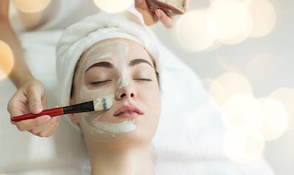 Cropped Hands Of Beautician Applying Facial Mask On Female Customer In Spa