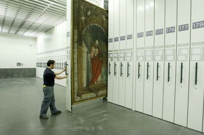 Un operario extrae un peine con obras de arte en los dep&oacute;sitos del edificio Jer&oacute;nimos del Prado.