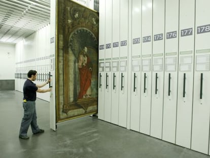 Un operario extrae un peine con obras de arte en los dep&oacute;sitos del edificio Jer&oacute;nimos del Prado.