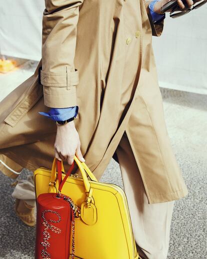 Trench con vuelo de Loewe, camisa de algodón de color azul de Dior, gafas de pasta de color gris de Oliver Peoples, pantalón camel de Pedro del Hierro, portadocumentos amarillo de Gucci, bolso tubular en color rojo con cadenas de Chanel, y reloj Dandy de piel y oro de Chaumet.