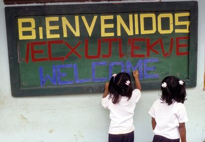 Tras dos años de no escuchar ni un solo disparo más, dos niñas alumnas de la Institución Educativa Toribío escriben un cartel de bienvenida a su escuela en español, inglés y en la lengua indígena local nasa yuwe, que las autoridades nasa se proponen rescatar para que no se pierda. 