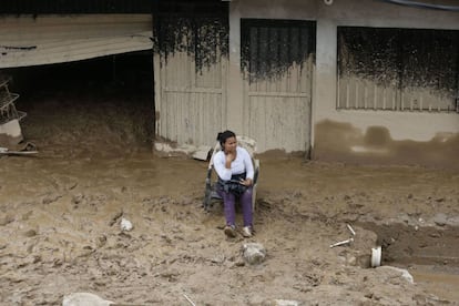 Una mujer espera sentada en el exterior de su vivienda cubierta de barro en Mocoa (Colombia).