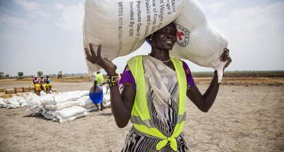 Una voluntaria carga un saco de semillas distribuido por la Cruz Roja Internacional en la ciudad de Thonyor, Sudán del Sur.