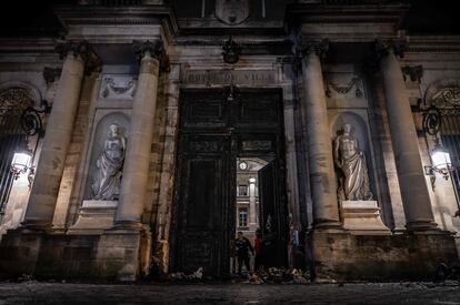 Varias personas junto a la puerta incendiada del Ayuntamiento de Burdeos durante las protestas, este jueves. 