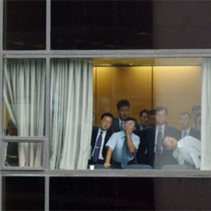 Un grupo de trabajadores de Hyundai mira por la ventana del edificio del que se arrojó el hijo del fundador de la empresa.