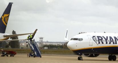 Dos operarios de Ryanair reparan los da&ntilde;os en un ala derecha de un avi&oacute;n en Sevilla.