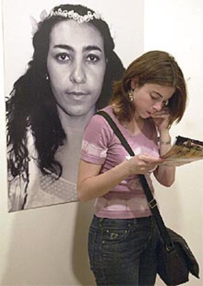 Una visitante consulta un catálogo delante de una de las obras de la artista Beth Moyses.