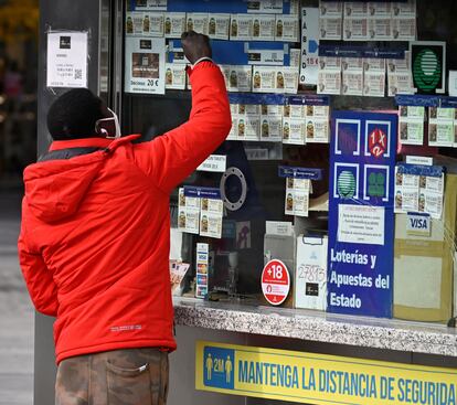 Un joven señala un billete de lotería en un establecimiento de Madrid.