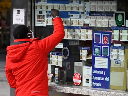 Un joven señala un billete de lotería en un establecimiento de Madrid.