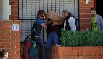 Plainclothes policemen take the suspect back into custody after a house search.