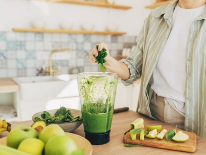 Young man preparing healthy green smoothie in kitchen