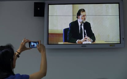 Una periodista saca una foto de una imagen de televisión del presidente de Gobierno, Mariano Rajoy.