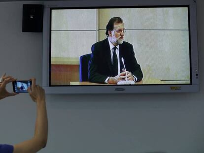 Una periodista saca una foto de una imagen de televisión del presidente de Gobierno, Mariano Rajoy.