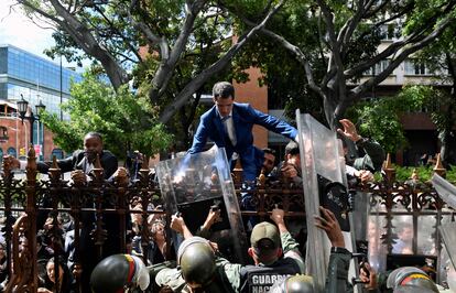 El líder opositor venezolano y autoproclamado presidente en funciones, Juan Guaidó, es ayudado a trepar por una barandilla en un intento de llegar al edificio de la Asamblea Nacional en Caracas, el 5 de enero de 2020. Se esperaba que Guaidó fuera reelegido presidente del Parlamento, pero solo los legisladores del régimen y los diputados de la oposición críticos con Guaidó pudieron ingresar al edificio.