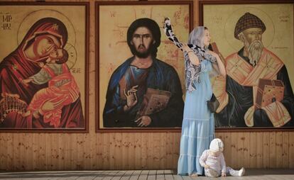 Una mujer se envuelve una bufanda alrededor del cuello, delante de unos grandes iconos durante una peregrinación del Domingo de Ramos ortodoxo en Bucarest, Rumania.