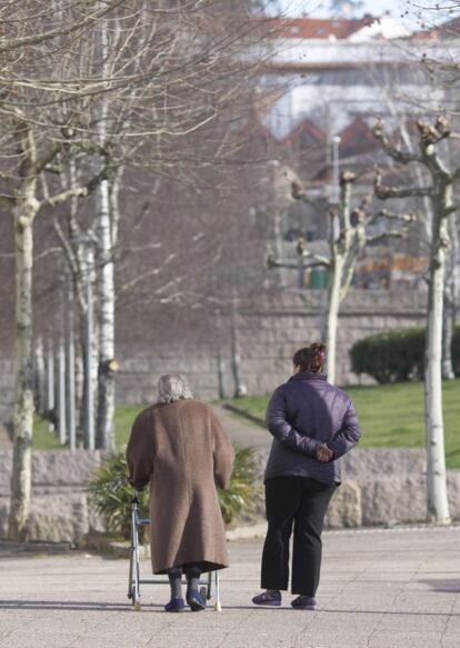 Una anciana, junto a su cuidadora, en un barrio de Santiago.