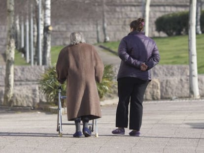 Una anciana, junto a su cuidadora, en un barrio de Santiago.