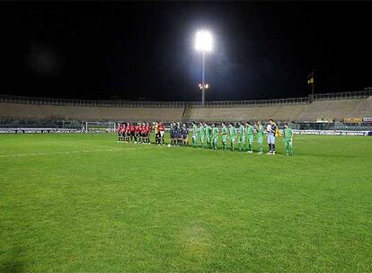 Los equipos del Livorno (izquierda) y del Espanyol, con el equipo arbitral en el centro, sobre el terreno de juego del estadio del conjunto italiano con las gradas vacías