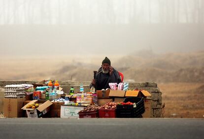 Un vendedor ambulante fuma una pipa de agua mientras espera clientes, en una mañana con niebla, en Srinagar (India).