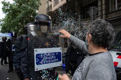 Una mujer tira confeti a los Mossos d'Esquadra en una ocupación de la sede de ERC en la calle Calàbria en protesta por el desahucio del bloque Llavors este martes por la mañana.