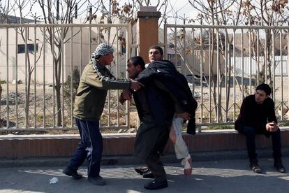 Un hombre traslada a un herido tras la explosión de un coche bomba en el centro de la capital afgana, el 27 de enero de 2018.