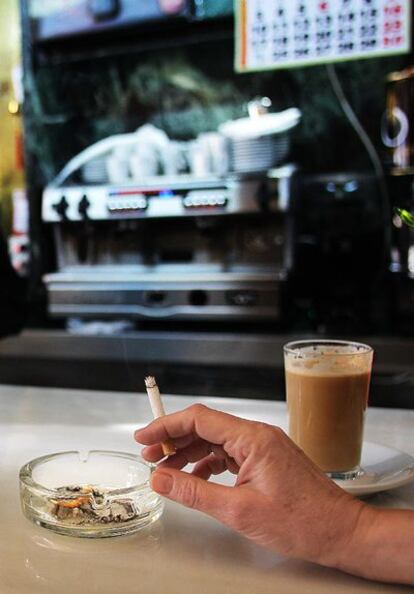 Un cliente fuma un cigarrillo en un bar insumiso.