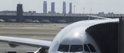 Un avión carga viajeros con la T4 de Madrid-Barajas de fondo.