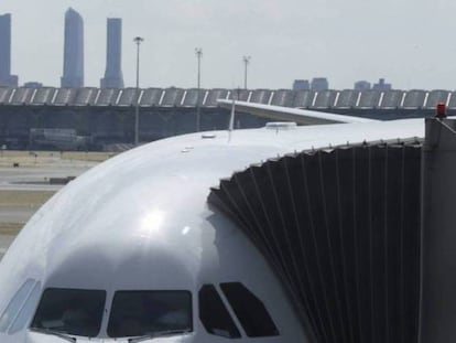 Un avión carga viajeros con la T4 de Madrid-Barajas de fondo.