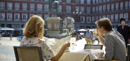 Two visitors to Madrid enjoy a drink in the sunshine of Plaza Mayor - but is anyone relaxing with a coffee?