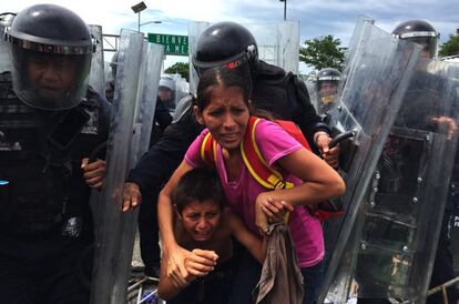 Una madre protege a sus hijos de las piedras que vuelan durante el enfrentamiento con la policía federal mexicana. 
