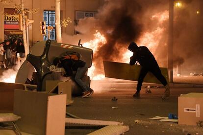 Protesters move trash containers to form a barricade.