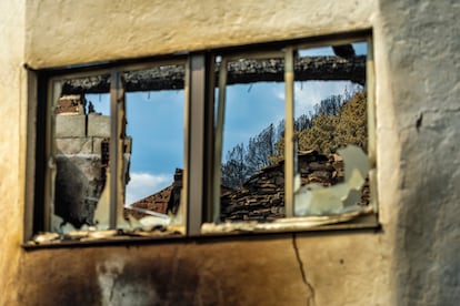 Reflejo de la devastación de San Vicente de Leira en una de las ventanas de sus casas derruidas.