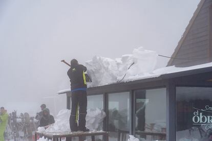 Un operario de la estación de esquí de Valdelinares (Teruel) retira bloques de nieve de un edificio del recinto.